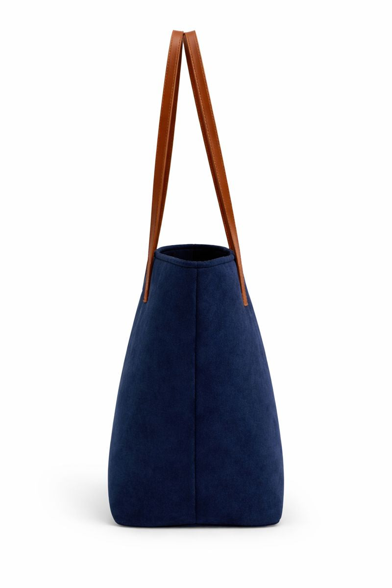 Navy blue tote bag with brown leather handles on a white background